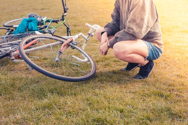 Young woman looking at her bicycle in park — Stock Photo, Image