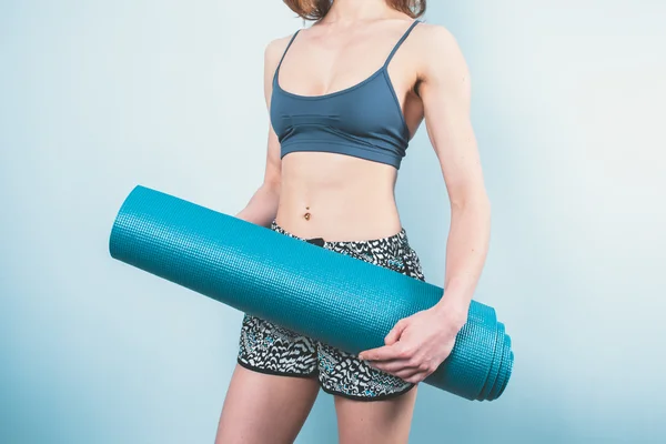 Athletische junge Frau mit einer Yogamatte — Stockfoto