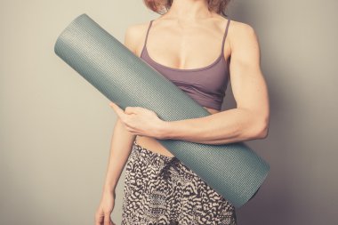 bir yoga mat tutan atletik genç kadın