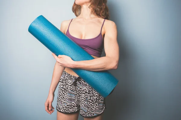 Bir yoga mat tutan atletik genç kadın — Stok fotoğraf