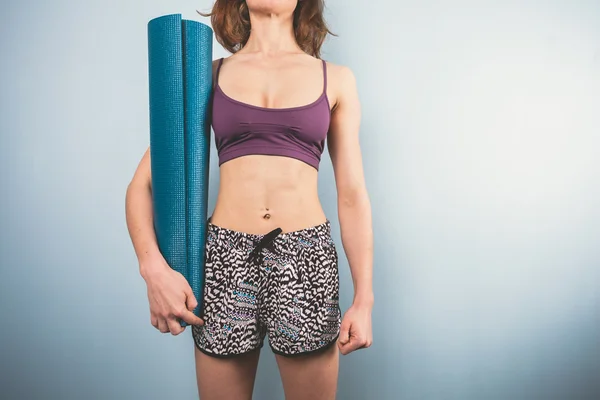 Athlétique jeune femme tenant un tapis de yoga — Photo