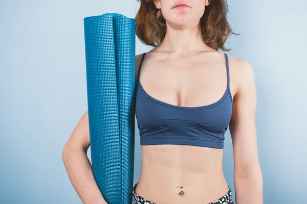 Giovane donna atletica con in mano un tappetino da yoga — Foto Stock