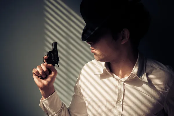 Man with gun by window — Stock Photo, Image