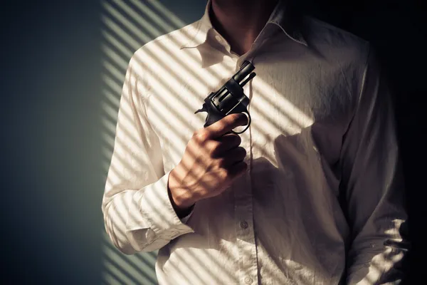 Man with gun by window — Stock Photo, Image