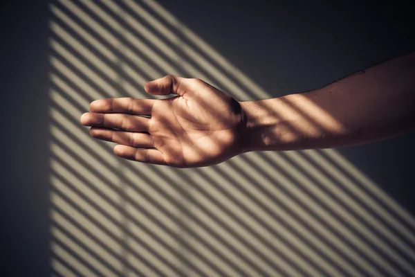 Man's hand met schaduwen van jaloezieën — Stockfoto