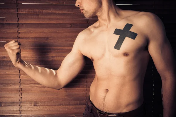 Young man flexing his muscles by window — Stock Photo, Image