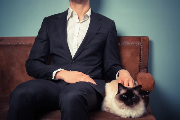 Genç adam ve kedi kanepede rahatlatıcı — Stok fotoğraf