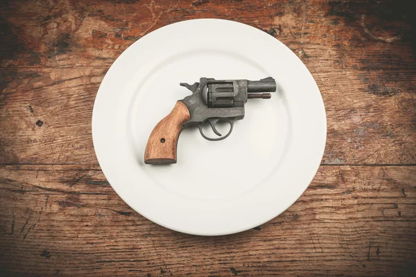 Gun on plate — Stock Photo, Image