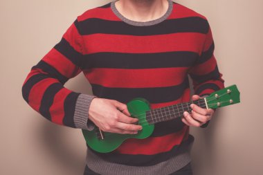 Man in striped jumper playing ukulele clipart