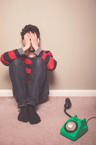 Moe en verdrietig man op verdieping met telefoon — Stockfoto