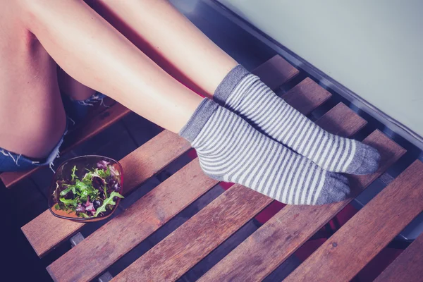 Woman's legs and a bowl of salad — Stock Photo, Image