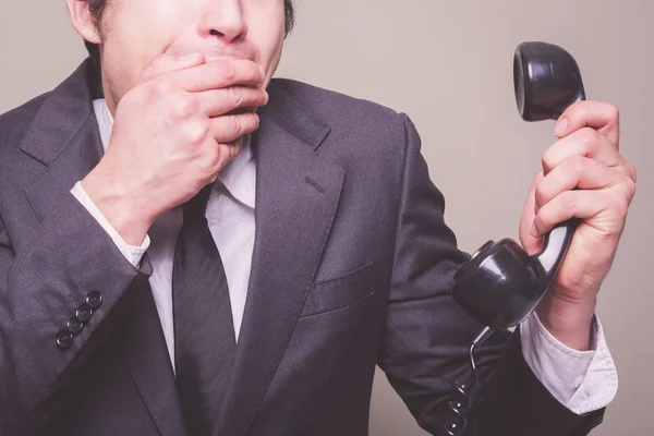 Businessman on phone covering his mouth — Stock Photo, Image