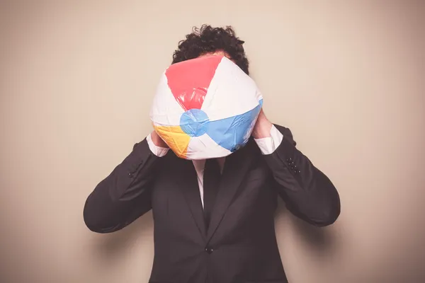 Businessman blowing up a beach ball — Stock Photo, Image