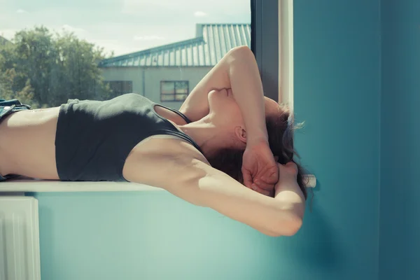 Mladá žena leží v okně — Stock fotografie