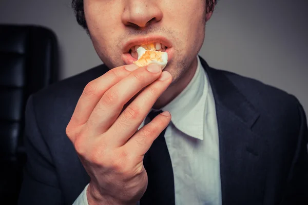 Businessman eating egg — Stock Photo, Image