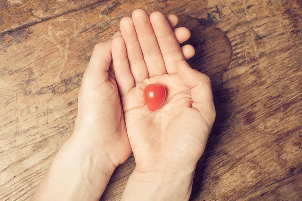 Mãos segurando o tomate em forma de coração — Fotografia de Stock