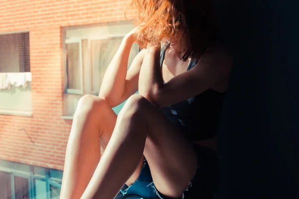 Young woman sitting in window and thinking — Stock Photo, Image