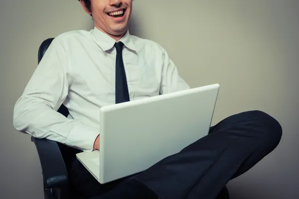 Бизнесмен в офисном кресле работает над ноутбуком — стоковое фото