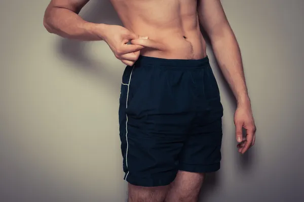 Fit young man pinching his stomach — Stock Photo, Image