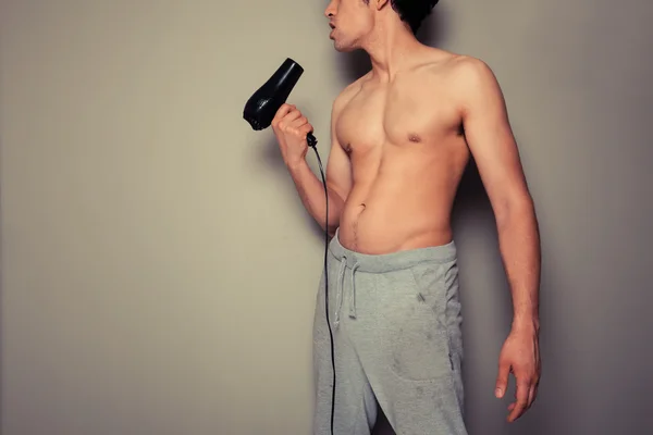 Athletic young man with a hair dryer — Stock Photo, Image