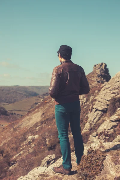 Молодой человек стоит в горах — стоковое фото