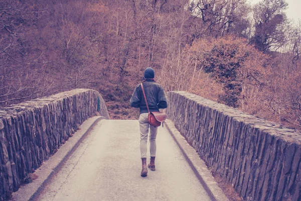 Jonge vrouw kruising brug in bos — Stockfoto