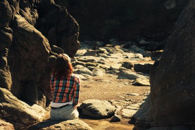 kayalık bir manzara içinde oturan genç kadın