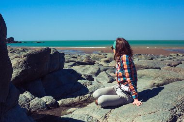 kayalık bir sahilde oturan genç kadın