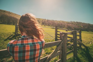Young woman by a fence on a ranch clipart