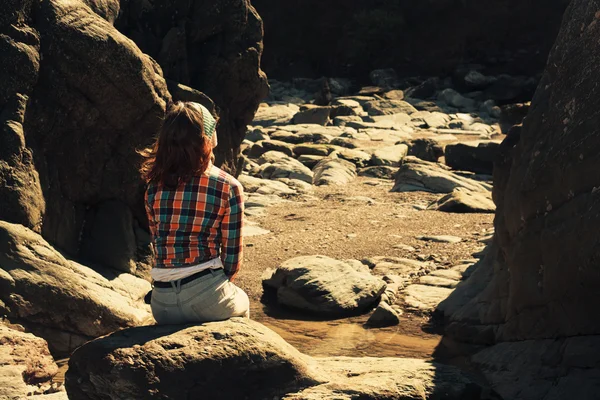 Jeune femme assise dans un paysage rocheux — Photo