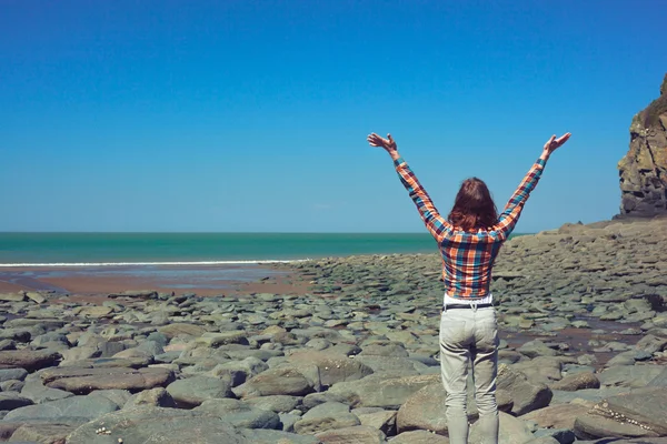 Mujer levantando los brazos en la playa — Foto de Stock