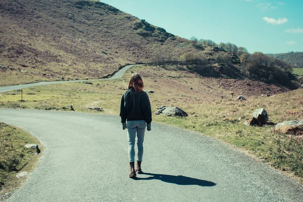 Mulher caminhando ao longo do caminho nas montanhas — Fotografia de Stock