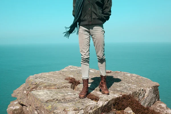 Frau steht auf einer Klippe am Meer — Stockfoto