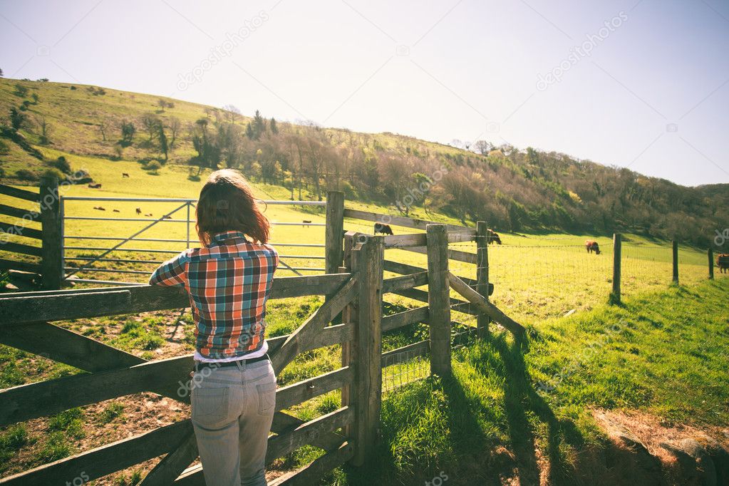 Young woman by a fence on a ranch
