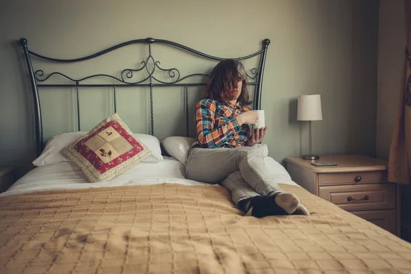 Νεαρή γυναίκα πίνοντας τσάι στο κρεβάτι — Φωτογραφία Αρχείου