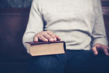 adam elini bir kitap üzerinde oturuyor