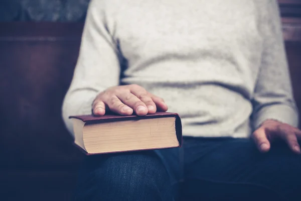 Homem sentado com a mão em um livro — Fotografia de Stock