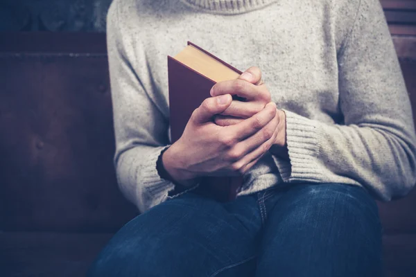 Nervous young man clutching book — Stock Photo, Image