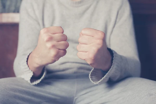 Hombre en sofá con los puños cerrados — Foto de Stock