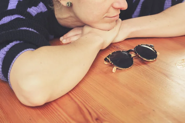 Jonge vrouw met zonnebril aan tafel — Stockfoto
