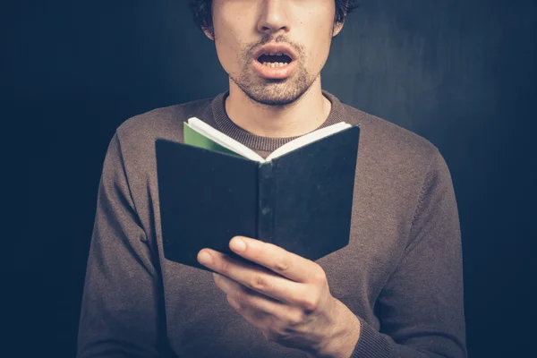 Verrast jonge man met een klein notitieboekje — Stockfoto
