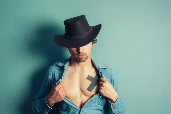 Jovem cowboy desabotoando sua camisa — Fotografia de Stock