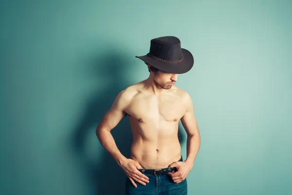 Shirtless cowboy opvallend een pose door blauwe muur — Stockfoto