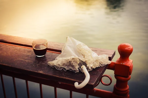 Coffee and umbrella on table by the lake — Stock Photo, Image