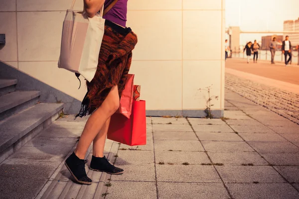 Mujer joven con bolsas de compras por escaleras al atardecer —  Fotos de Stock