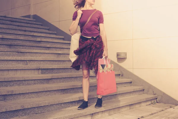 Mujer joven con bolsas de compras por escaleras al atardecer — Foto de Stock