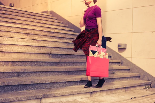 Mujer joven con bolsas de compras por escaleras al atardecer —  Fotos de Stock