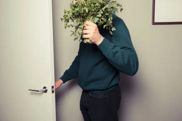 Young man with parsley is answering the door — Stock Photo, Image