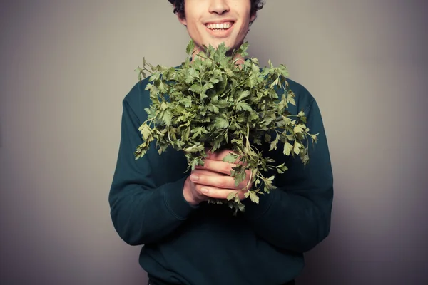 Happy young man with a big bunch of parsley — Stock Photo, Image