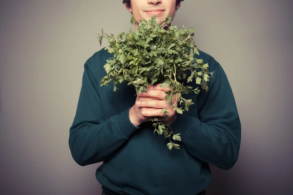 Happy young man with a big bunch of parsley — Stock Photo, Image